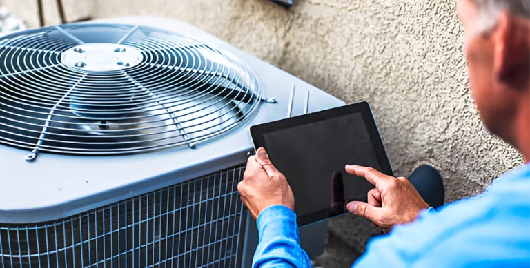 A technician checking an outdoor AC unit with a tablet